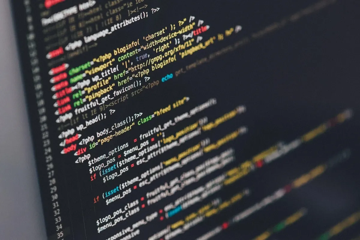 Programista skupiony na pracy przy komputerze, analizujący linie kodu i dane na ekranie.